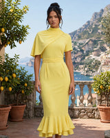 Enchant lemon twisted cape midi dress worn on a coastal terrace