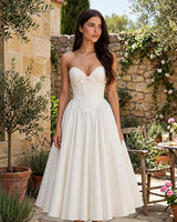 Prim ivory corset midi dress worn in a Mediterranean courtyard