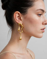 Rhea gold molten drop earrings — worn close-up