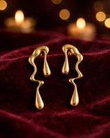 Rhea gold molten drop earrings — on velvet